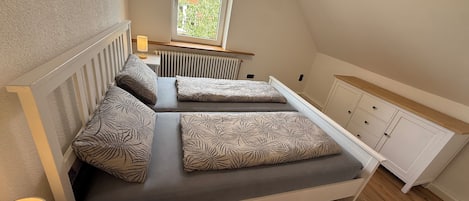 Ein Schlafzimmer mit einem Bett, einem Fenster, einer Heizung und einem Schrank.