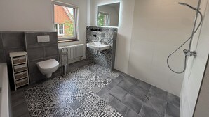 Ein Badezimmer mit Toilette, Waschbecken, Dusche und Fliesenboden mit Muster.