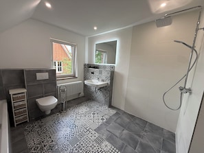 Ein Badezimmer mit Toilette, Waschbecken, Dusche und Fliesenboden mit Muster.