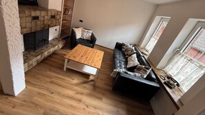 Ein Wohnzimmer mit Kamin, einer Couch, einem Couchtisch und einem Bücherregal.