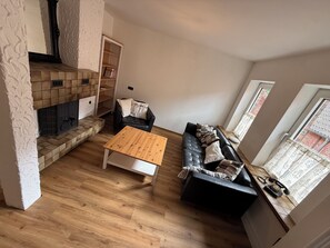 Ein Wohnzimmer mit Kamin, einer Couch, einem Couchtisch und einem Bücherregal.