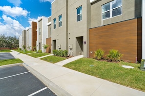 A modern building with a parking lot, green lawns, and a clear sky. - Chic Home Just 15 Min to Disney (Kissimmee)