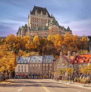 A historic building with a prominent tower, surrounded by autumn-colored trees and a street with pedestrians. - Logement au centre Ville de Québec (Québec City)