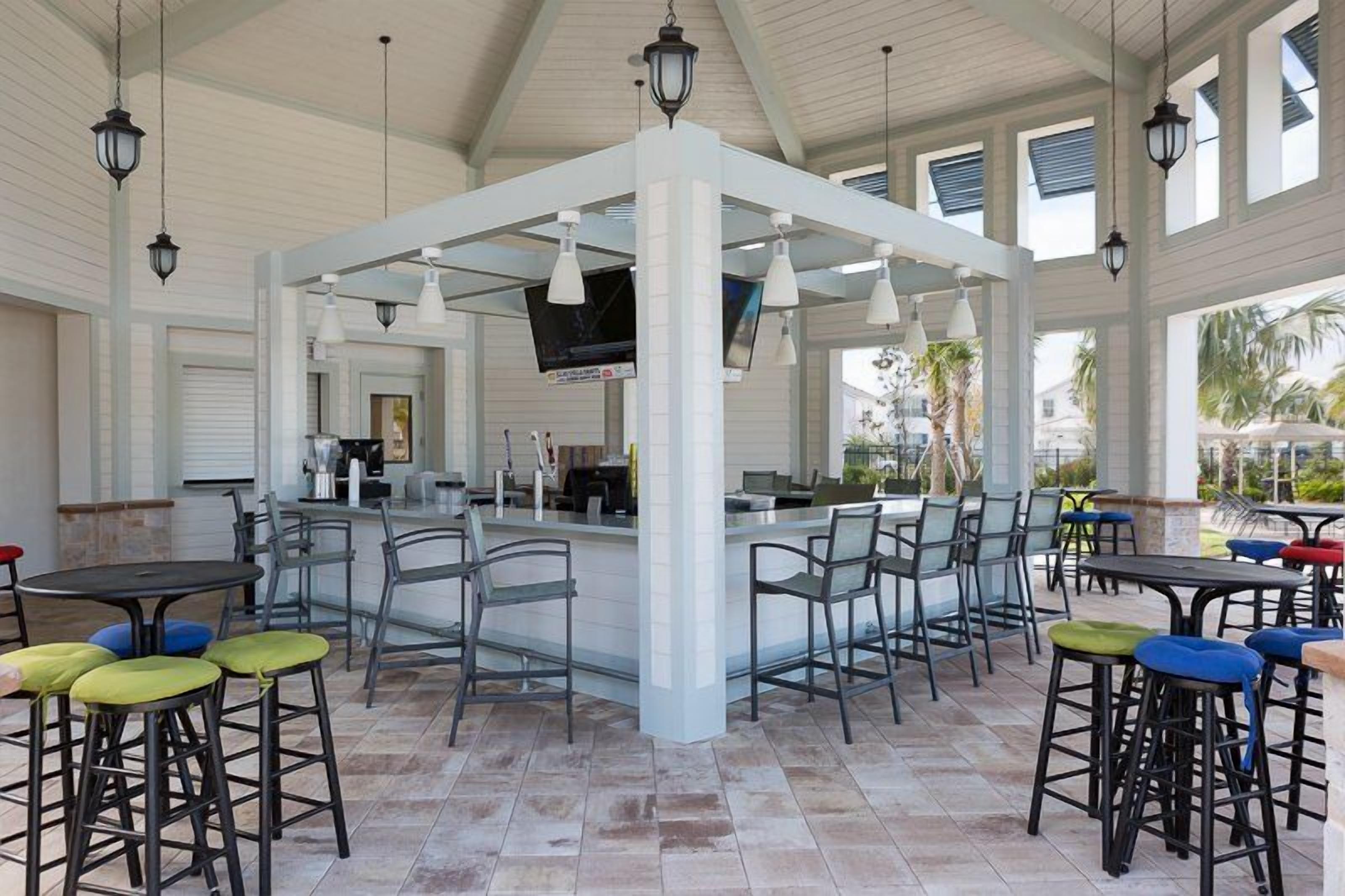 An indoor bar area with multiple seating arrangements, a central bar counter, and hanging light fixtures.