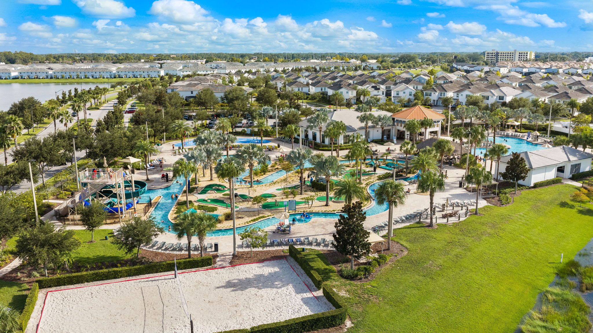 A resort with multiple swimming pools, a large sandy area, and a variety of trees.