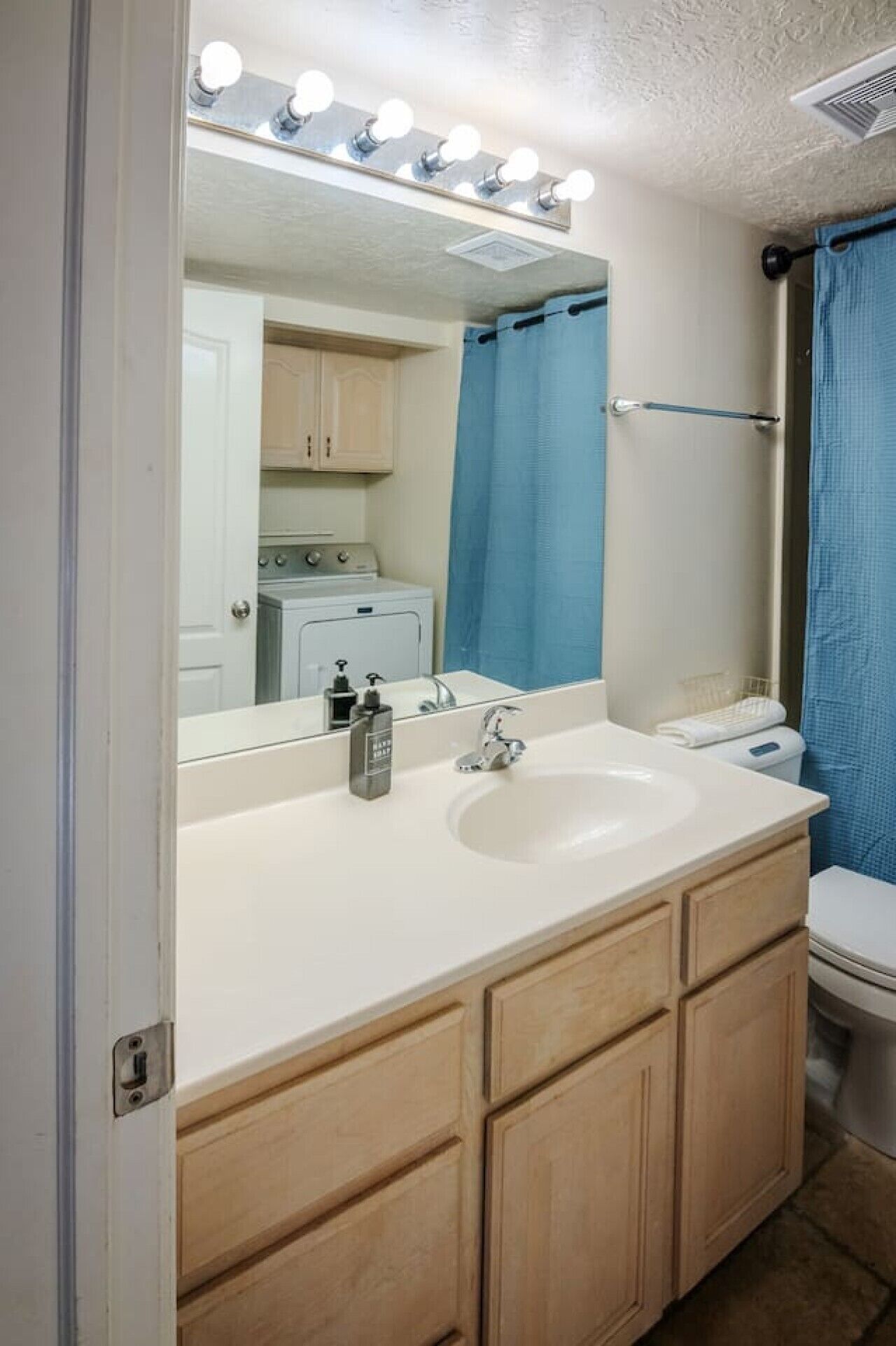 A bathroom with a vanity, sink, mirror, and a shower curtain.