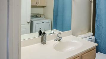 A bathroom with a vanity, sink, mirror, and a shower curtain.