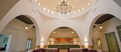 A spacious lobby with arched ceilings, a central chandelier, and seating areas.