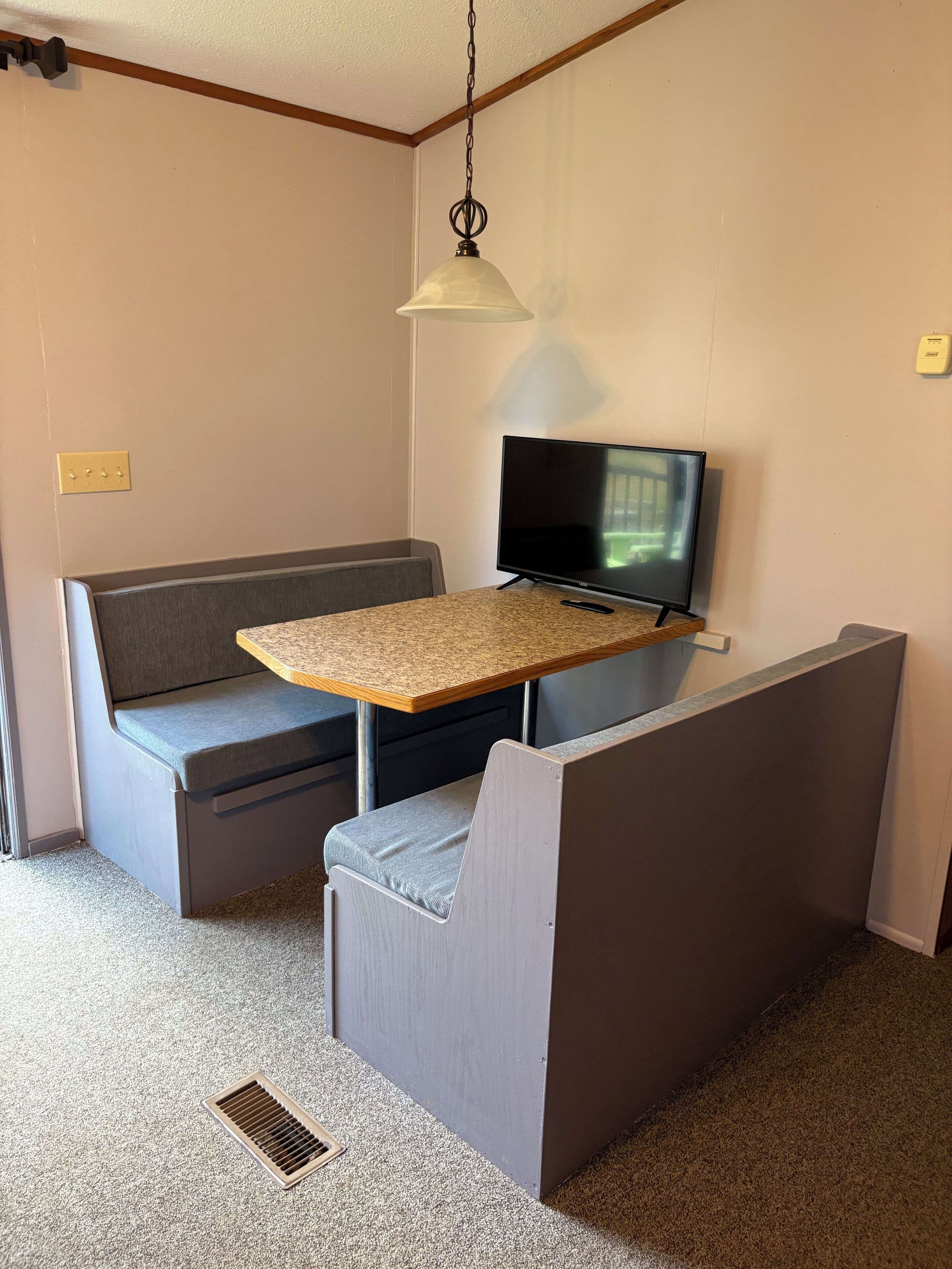 A small room with a kitchenette, a television, a sofa, and a table.