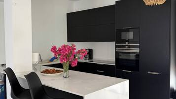 Una cucina moderna con isola centrale, pensili neri e lampada a sospensione.
