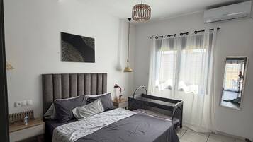 Una camera da letto moderna con un letto grande, un comodino, una lampada a sospensione e una finestra con tende.