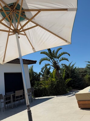 An outdoor seating area with a large umbrella, a table, and chairs.