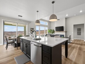 Een moderne keuken met een centraal eiland, ingebouwde apparatuur en een eetgedeelte met uitzicht.