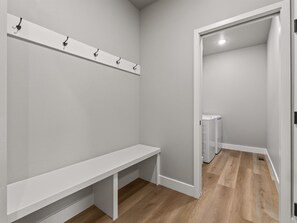 A room with a bench, a coat rack, and a door leading to a bathroom. - NEW! Mesa View Modern: Luxury Living (Grand Junction)