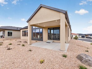 A modern house with a covered patio, large windows, and a gravel driveway. - NEW! Mesa View Modern: Luxury Living (Grand Junction)