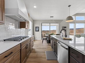 A modern kitchen with a central island, wooden cabinets, and a view of the landscape. - NEW! Mesa View Modern: Luxury Living (Grand Junction)