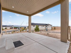 A covered outdoor area with a concrete floor, a small tree, and a building in the background. - NEW! Mesa View Modern: Luxury Living (Grand Junction)