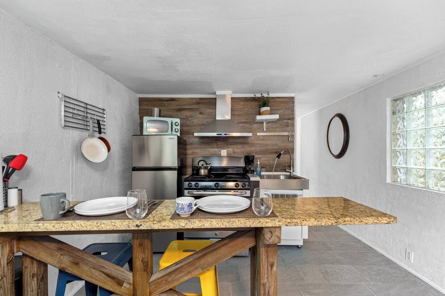 A modern kitchen with a granite countertop, stainless steel appliances, and a wooden backsplash.