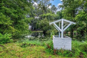 A gazebo structure with a white roof and a stone base, surrounded by lush greenery and a pond. - Riverfront View w/ Kayaks in the midst of Tampa's Best Restaurant District (Tampa)