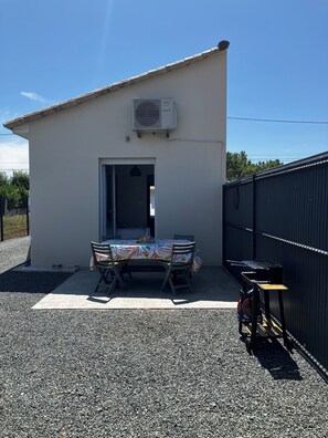 Ein kleines Gebäude mit einer Tür, einem Tisch mit Stühlen und einer überdachten Außenbereich-Sitzgelegenheit.