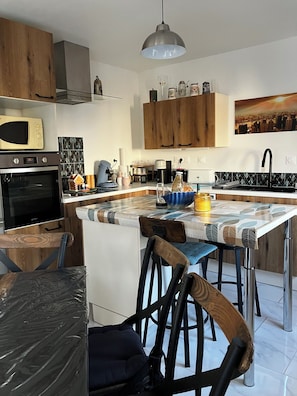 Eine moderne Küche mit Holzausbau, einem eingebauten Backofen, einer Kaffeemaschine und einem Essbereich mit Tisch und Stühlen.