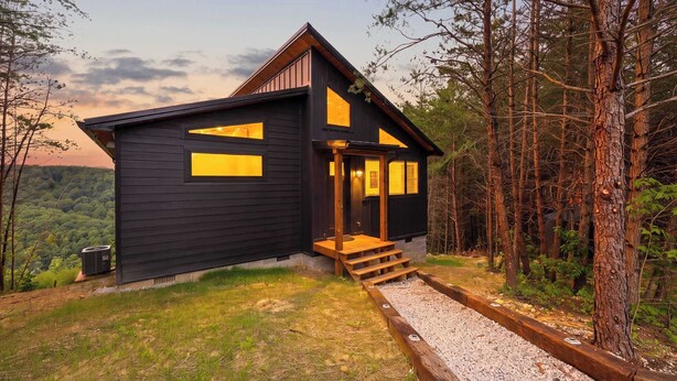 A cabin with a sloped roof, large windows, and a wooden deck. - Sugar Maple Cabin - Romantic, Sauna, View, Hot Tub (Rogers)