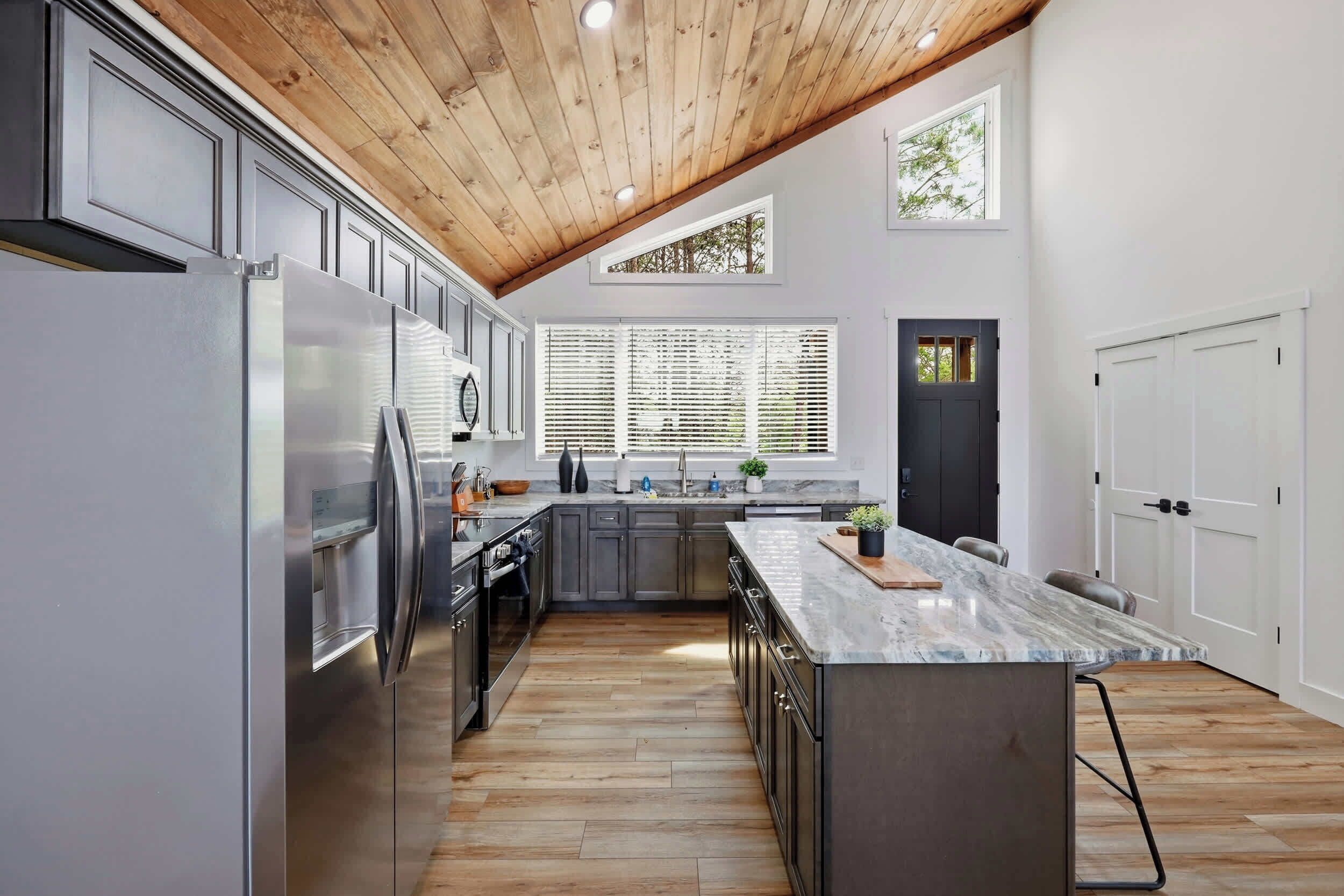Une cuisine moderne avec un plafond en bois, des appareils électroménagers intégrés et un grand îlot central.