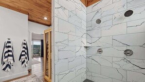 A modern bathroom with white marble tiles and a shower area. - Sugar Maple Cabin - Romantic, Sauna, View, Hot Tub (Rogers)