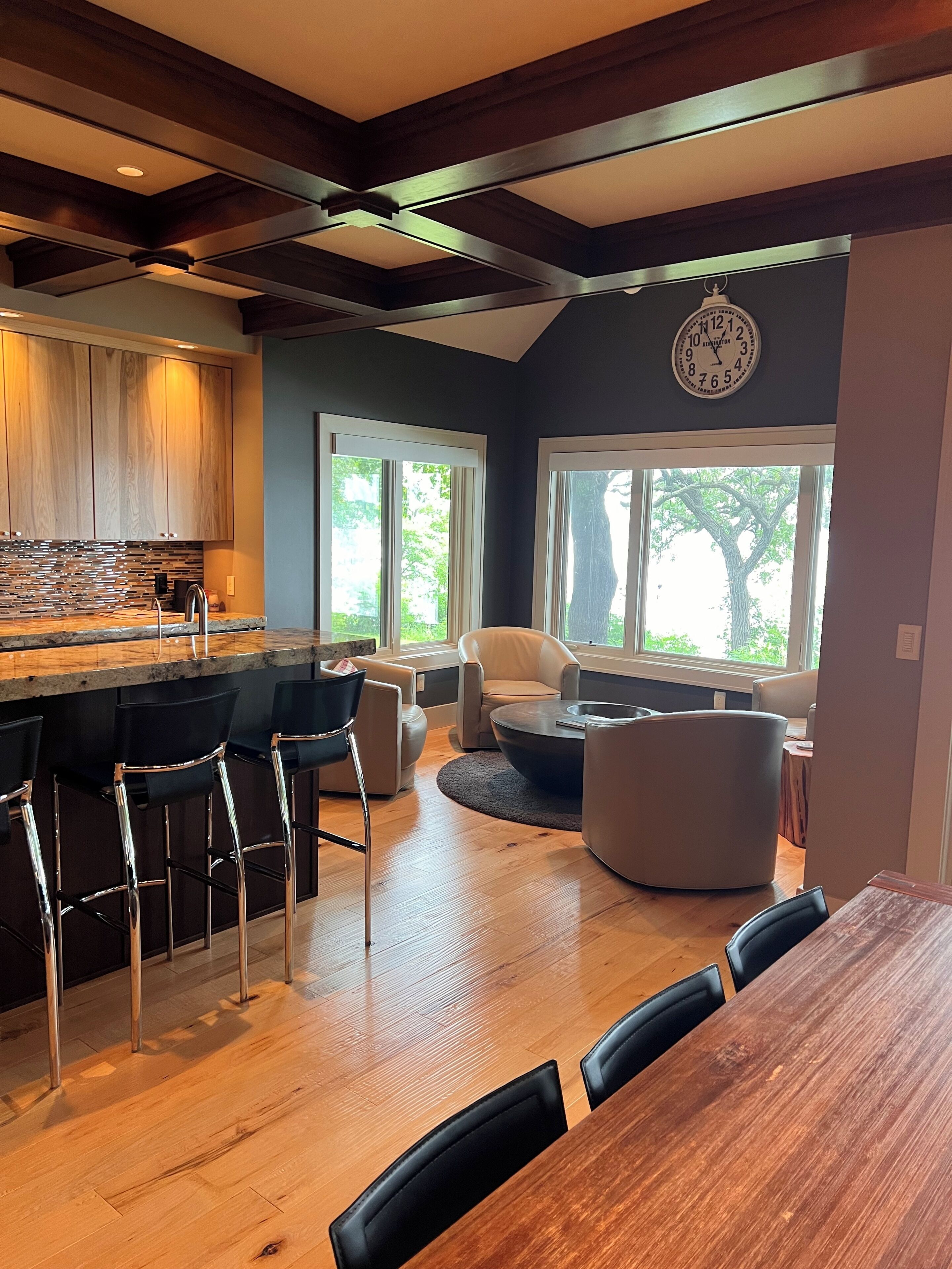 A modern kitchen with a bar area, wooden flooring, and a dining space with a large table and chairs.