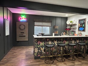 Eine Bar mit Dartscheibe, Barhocker und einer Neonreklame.