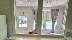 A room with a wooden table, a window with curtains, a white cabinet, and a tiled floor. - Farmville Lake House minutes from H-SC and Longwood (Farmville)