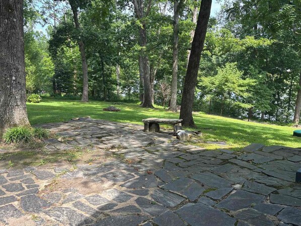 A stone-paved area with a stone bench surrounded by trees.