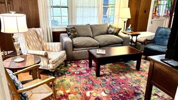 Un salon comprenant un canapé, des fauteuils, une table basse et un tapis à motifs.