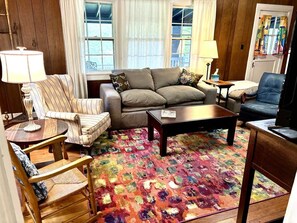 A living room with a sofa, armchairs, a coffee table, and a patterned rug.