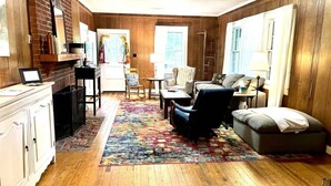 A cozy living room with a fireplace, wooden floors, a colorful rug, and a comfortable seating area. - Farmville Lake House minutes from H-SC and Longwood (Farmville)