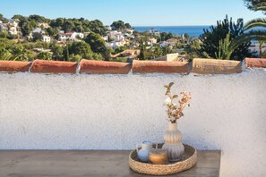 A balcony with a view of a coastal town, a white wall, and a small table with a vase and candles. - Casa Amandine, within walking distance of La Fustera Beach (Benissa)