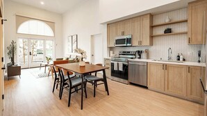 A modern kitchen with wooden cabinets, stainless steel appliances, and a dining area with a wooden table and chairs.