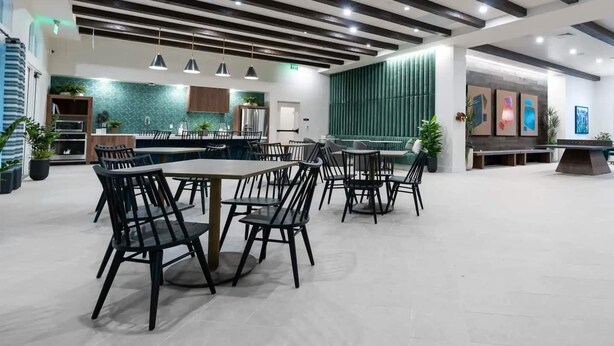 A spacious dining area with modern furniture and a kitchen in the background.