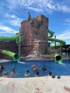 A water park with a pool, green slides, and a rocky structure. - 1-bedroom Sandy Beach condo with ocean view and AC (Puerto Peñasco)