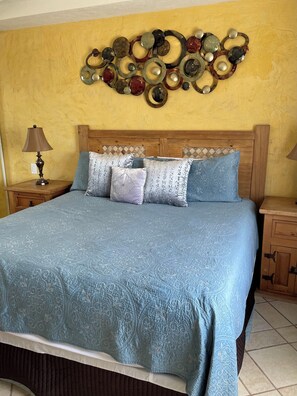 A bedroom with a bed, wooden headboard, and a wall decoration. - 1-bedroom Sandy Beach condo with ocean view and AC (Puerto Peñasco)