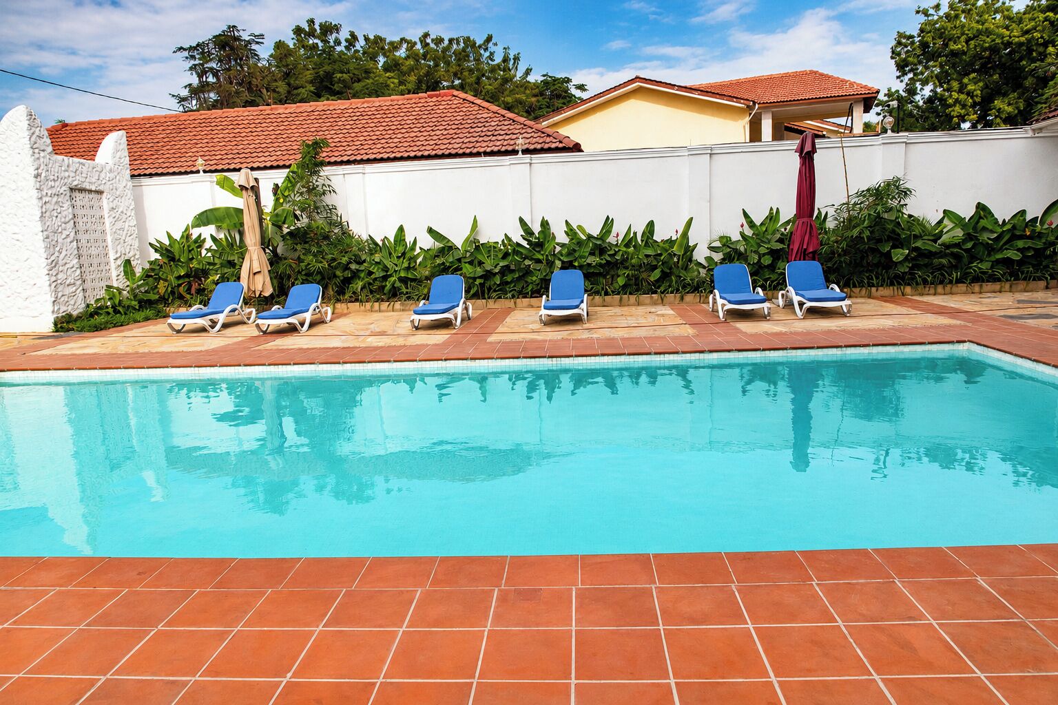 A swimming pool with blue lounge chairs and a tiled deck.