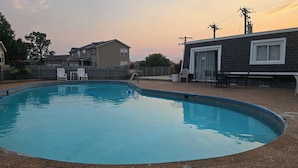 A swimming pool with a deck, surrounded by a wooden fence and houses. - Wobbly Glaize Getaway! Cozy Lake Condo near Wobbly Boots and Grand Glaize Bridge (Osage Beach)