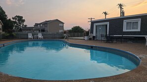 A swimming pool with a deck, surrounded by a wooden fence and houses. - Wobbly Glaize Getaway! Cozy Lake Condo near Wobbly Boots and Grand Glaize Bridge (Osage Beach)