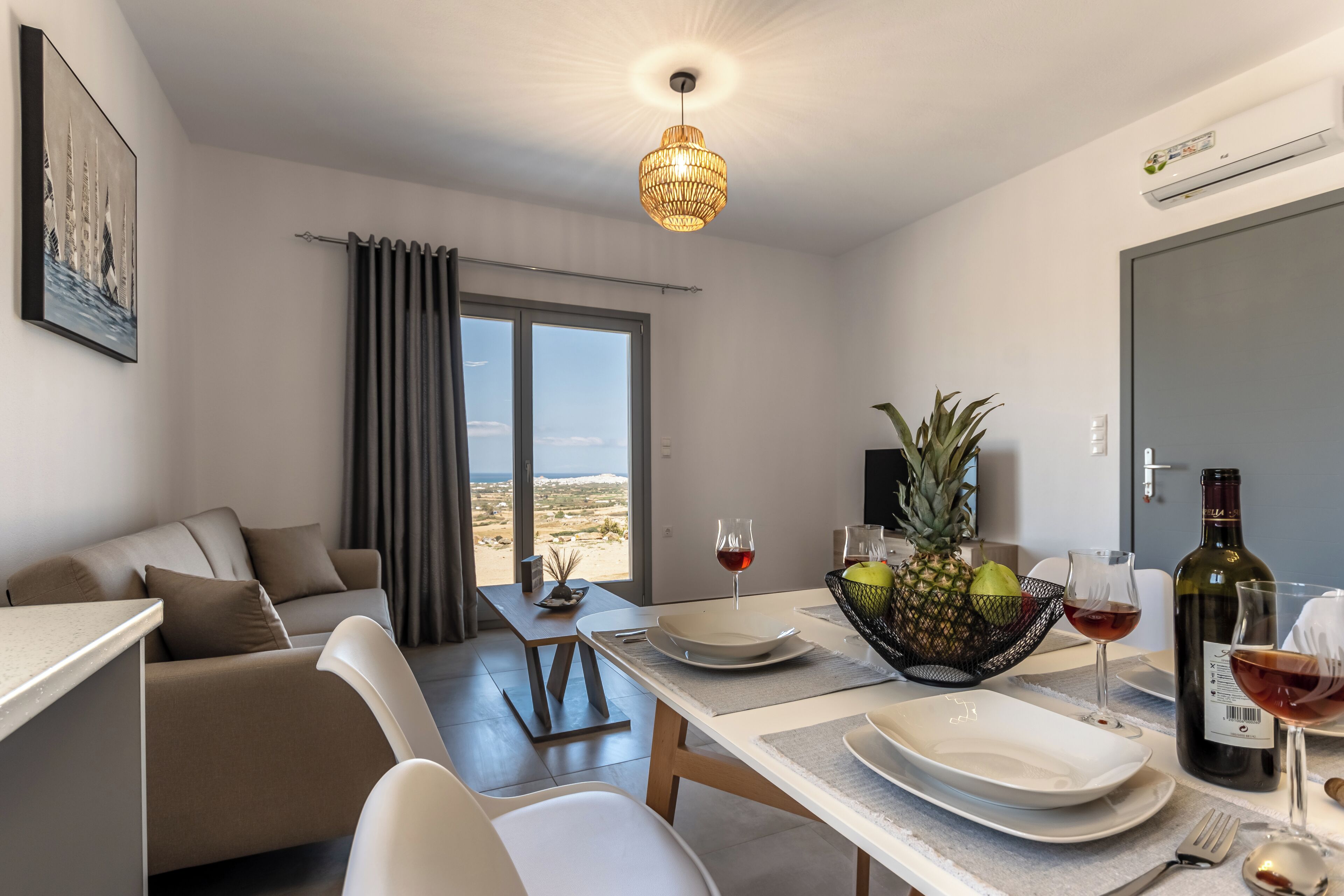 A modern living room with a dining area, a view to the outside, and a table set for a meal.