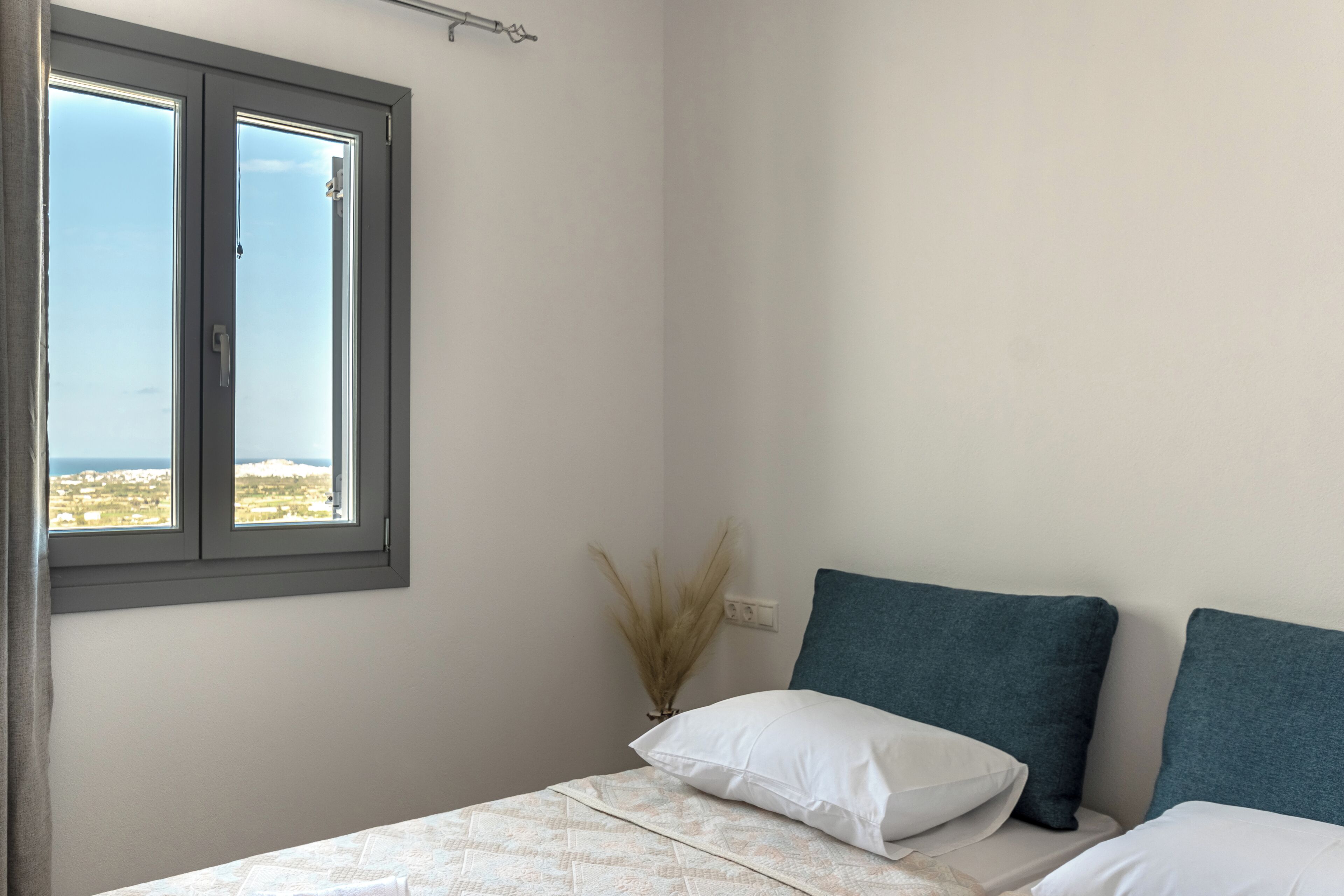 A bedroom with a bed, a window, and a view of a cityscape.