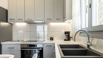 A modern kitchen with grey cabinets, a built-in oven, a coffee maker, and a sink.