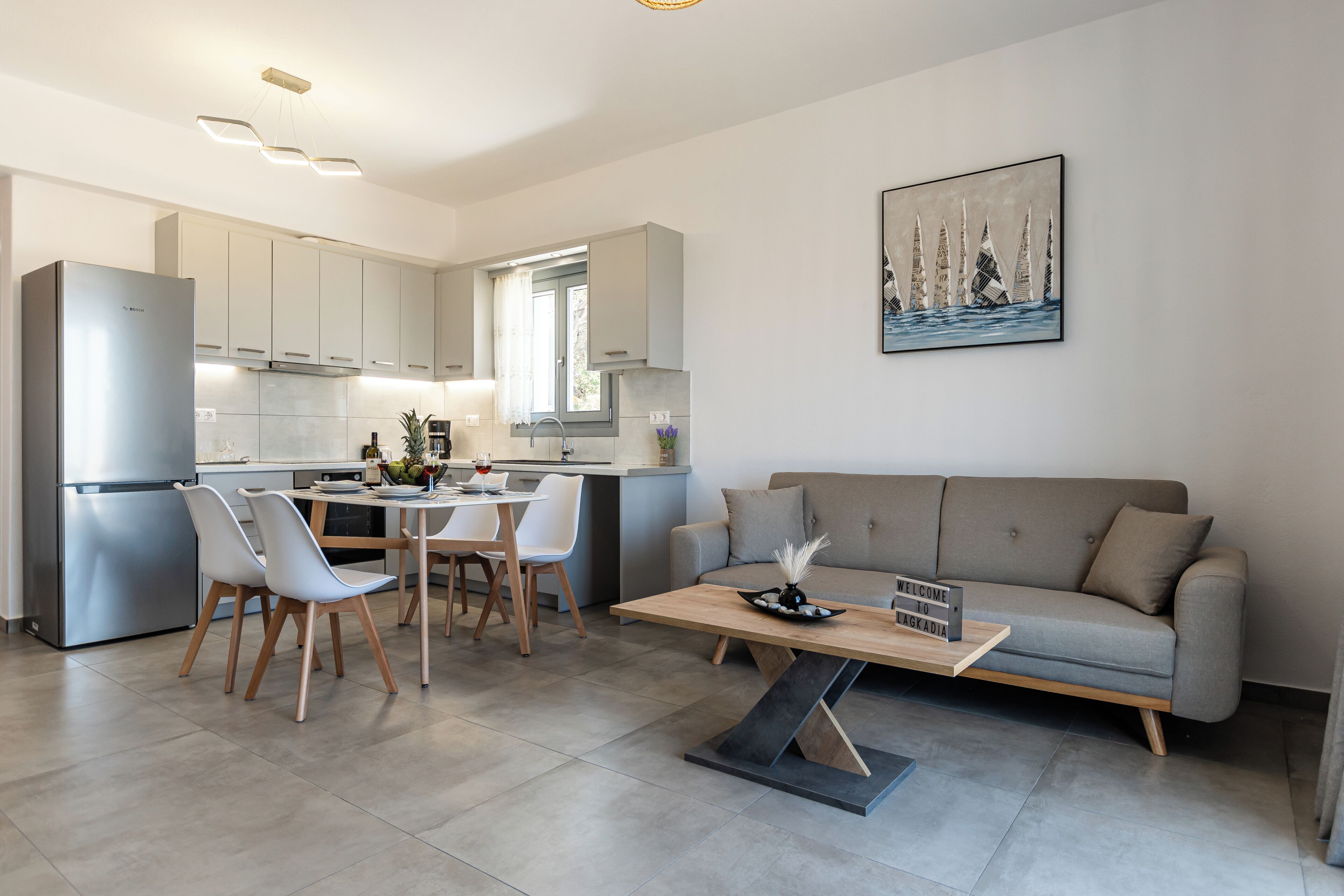A modern kitchen with a built-in refrigerator, a dining area with a table and chairs, and a living area with a sofa and a coffee table.