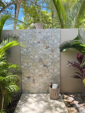 A wall with a tropical leaf pattern, a small birdhouse, and a woven basket. - Brand-New Luxury Villa · Private Pool · 5-Min Walk to Playa Cosón (Las Terrenas)