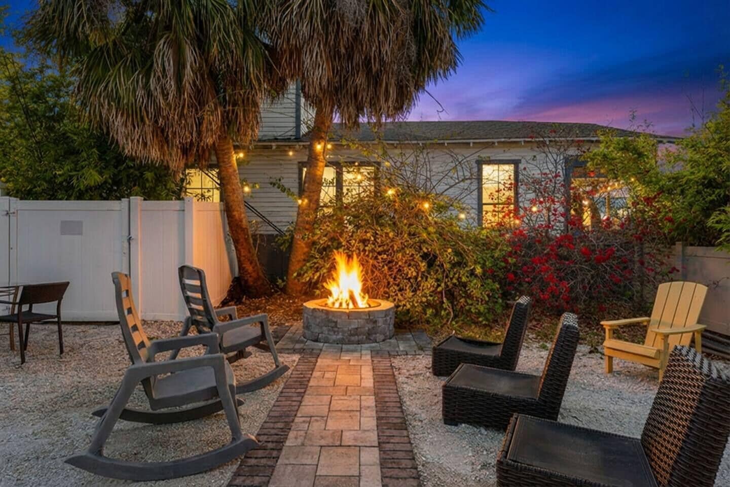 A patio area with outdoor seating, a fire pit, and a house in the background.
