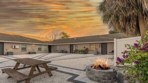 A courtyard with a fire pit, picnic table, and a building with multiple windows and a door. - Magnolia House; Grille/Firepit/Patio View! (Tampa)